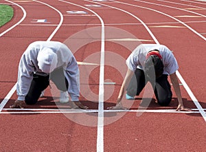 Two boys in lanes on a red track ready to run a 100 meter race at practice