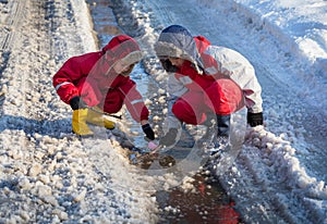 Two boys launching the paper boat at the creek