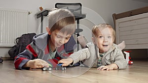 Two boys lying on floor and having a fight with toys. Children playing alone, development and education, games at home.