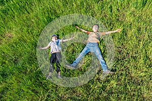 Two boys are lying on the grass, top view of happy and joyful friends