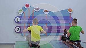 Two boys makes sport exercise on training apparatus in museum of popular science