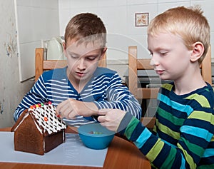 Two boys making gingerbread house