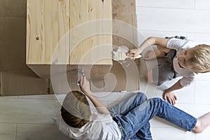 Two boys painting wooden curbstone with brush. Children renovating table. Top view