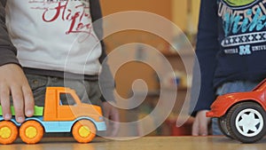 Two boys play toy model cars at the table