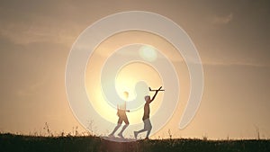 Two boys play with a wooden plane at sunset. Silhouette of children playing with airplane. Dreams of flying. The concept