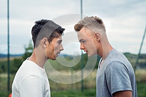 Two boys on playground looking at each other with hate.