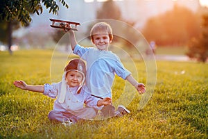 Two boys, playing with airplane on sunset in the park