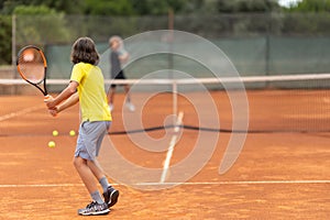Two boys playing friendly tennis match on the court