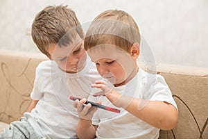 Two boys playing games on smartphone at home