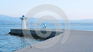 Two boys playing on the pier near lighthouse. Young tourists having fun on quayside. Positive emotions. Fresh air