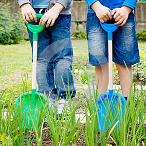 Two boys playing with plastic shovels in the garden