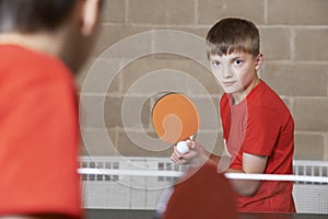 Two Boys Playing Table Tennis Match In School Gym