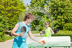 Two boys playing together ping pong outside