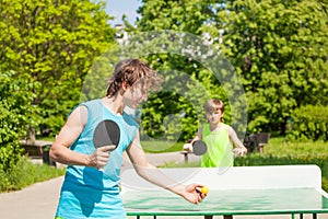 Two boys playing together ping pong outside photo