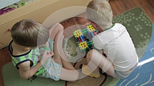 Two boys plays with constructor on the floor