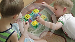 Two boys plays with constructor on the floor