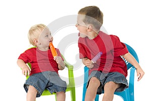 Two boys with popsicles on lawn chairs