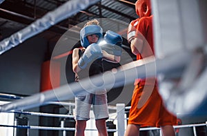 Two boys in protective equipment have sparring and fighting on the boxing ring