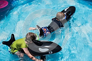 Two boys riding floats in backyard pool