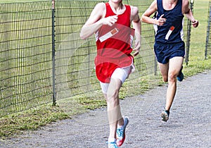 Two boys running a cross country race on a gravel path