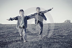 Two boys running together on meadow, sepia toned