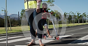 Two boys with school bags riding scooters and crossing the road