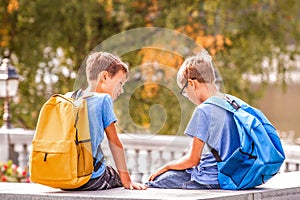 Two boys after school, sitting on bench and talking