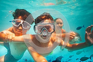 Two boys with scuba masks dive underwater in sea