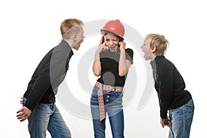 Two boys are shouting at a girl, the girl is standing in a helmet in a helmet and plugged her ears