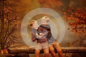 Two boys sitting on a bench in the woods