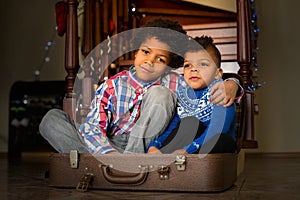 Two boys sitting inside suitcase.