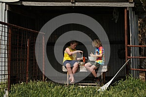Two boys sitting in small shed making slime for home schooling science experiment