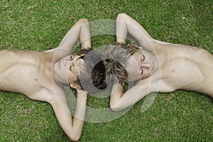 Two boys sleep lying on a green grass