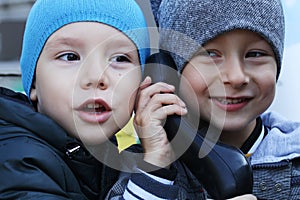 Two boys are speaking on the payphone and joking