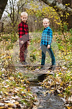 Two boys stand on pond under stream