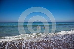 Two boys surfing together off of the beach of the Pacific Ocean