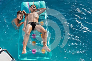 Two boys swim in the pool on an air mattress, happy childhood, summer concept