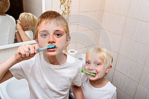 Two boys thoroughly brush their teeth in the bathroom. Morning hygiene