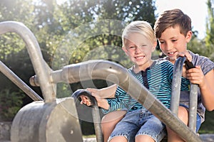 Two boys using digger on adventure playground in park