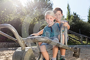 Two boys using digger on adventure playground in park