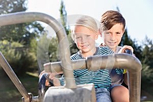 Two boys using digger on adventure playground in park