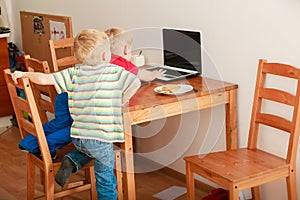 Two boys using laptop computer playing games