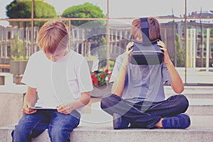 Two boys with virtual reality goggles and tablet computer