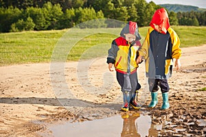Two boys walking through a mud puddle