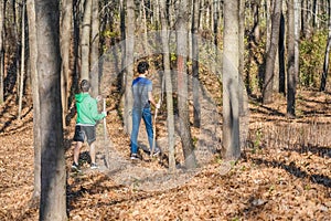 Two Boys with Walking Sticks Walking Through Forest photo