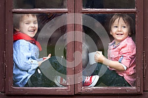 Two boys on the window, laughing and drinking tea