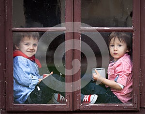 Two boys on the window, laughing and drinking tea