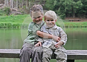 Two boys on wooden bench at the lake