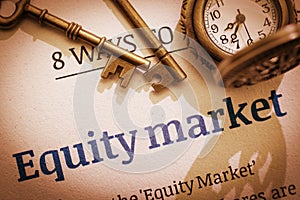 Two brass keys and a pocket watch on an equity market principal / fundamental document. photo