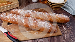 Two bread baguettes on a cutting board on on a wooden table